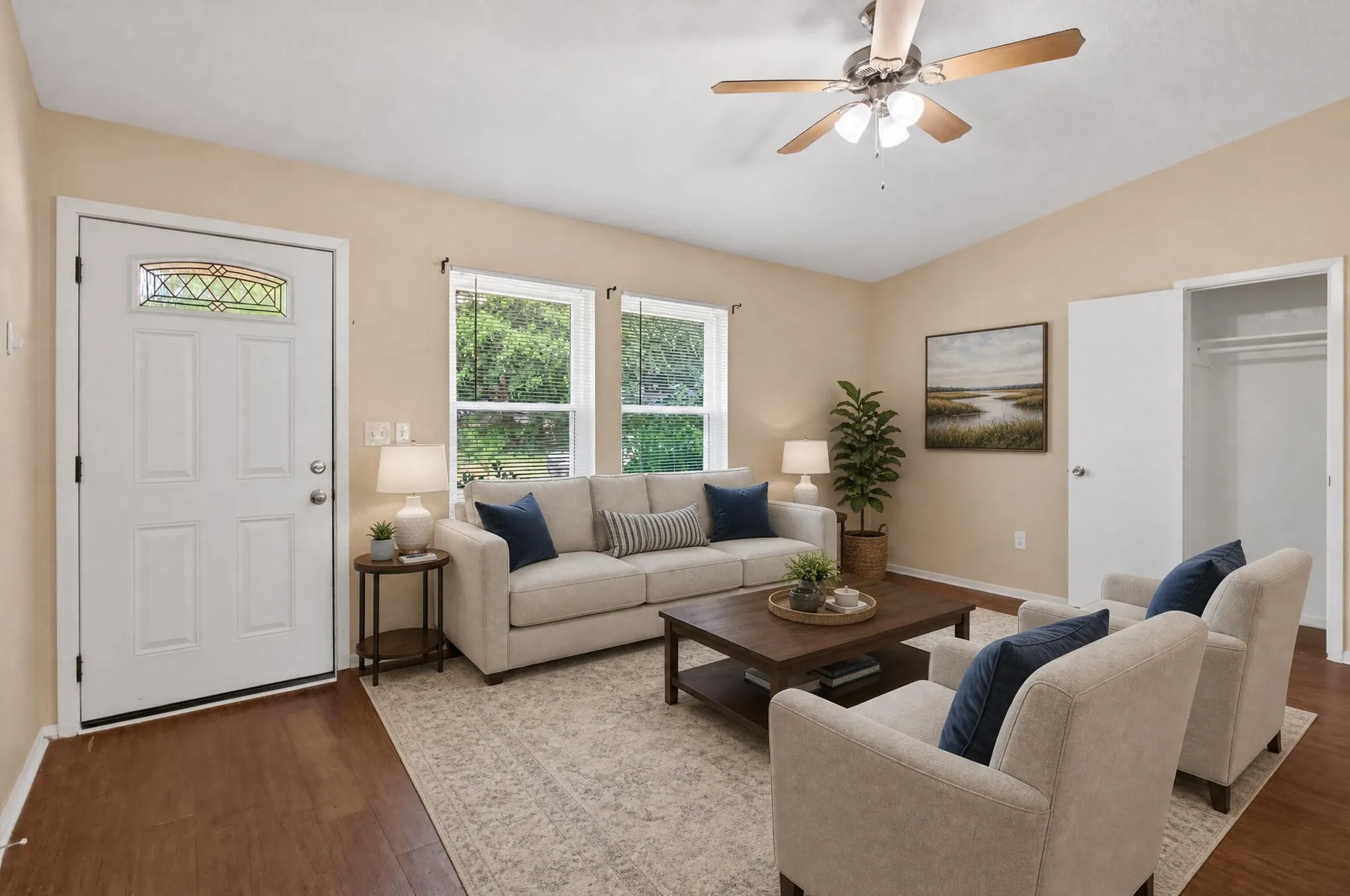 Virtually staged living room with sofa, chairs, rug, lamps, and wall art